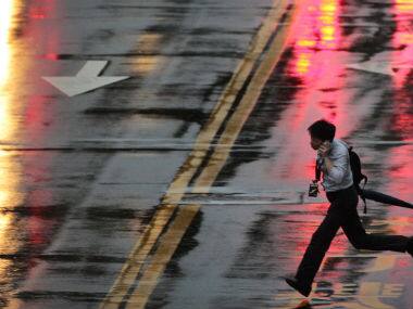 A man runs to make the crossing light through strong winds and rain from approaching Typhoon Matmo in Taipei, Taiwan. Associated Press