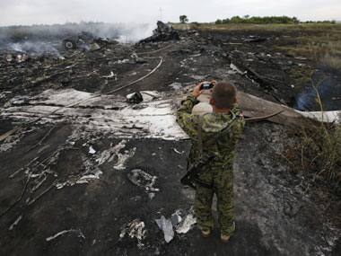 A pro-Russia rebel takes pictures of the crash site. Reuters.