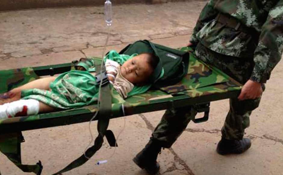 An injured child is carried by paramilitary policemen on a stretcher after an earthquake hit Longtoushan township of Ludian county, Yunnan province August 3, 2014. A magnitude 6.3 earthquake struck southwestern China on Sunday, killing at least 26 people in a remote mountainous area of Yunnan province, causing some buildings to collapse including a school. REUTERS