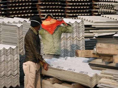 In this Nov. 23, 2013 photo, a worker covers his face with a handkerchief as he sees people photographing him and his coworker handling asbestos sheets at the Ramco Industries Ltd. factory in Bhojpur district of Bihar. AP 