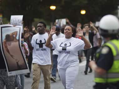 Protestors demonstrate past a police officer while marching through downtown in response to the fatal shooting of Michael Brown. AP 