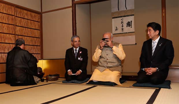 Modi and Abe kneeling and drinking tea. AFP