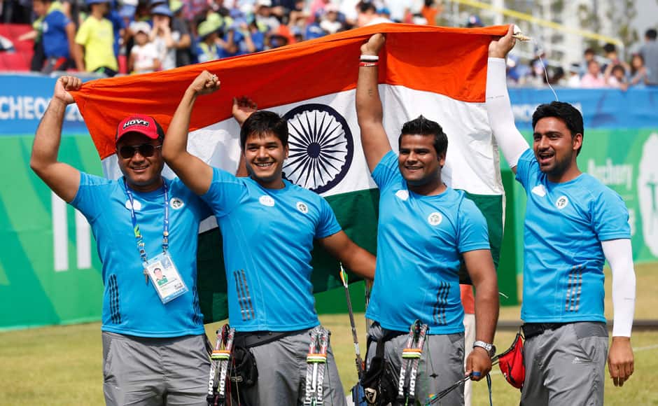 Sandeep Kumar, Raijat Chauhan, Abhishek Verma and coach Ranjan Singh hold the national flag after winning the compound men's team gold medal archery match. 
