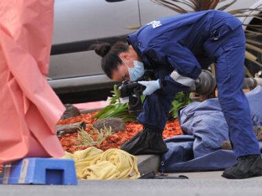 A forensic officer documents objects including a blanket at the scene of a fatal shooting at Endeavour Hills Police Station in Melbourne. AP