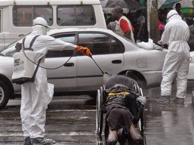 Health workers spray the body of a amputee suspected of dying from the Ebola virus with disinfectant, in a busy street in Monrovia, Liberia. AP