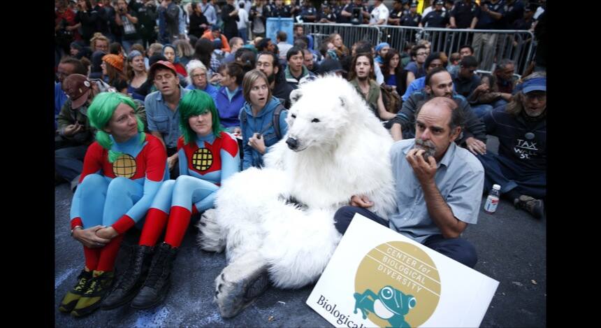 Protesters, including one dressed as a polar bear, sit at the intersection of Wall St. and Broad St. in New York, Monday, Sept. 22, 2014. The protesters were trying to draw attention to the connection between capitalism and environmental destruction. Eventually at least fifty protesters that would not move from the intersection were taken into custody. (AP Photo/Seth Wenig)