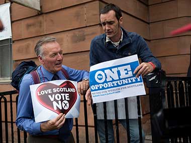 A No campaign supporter and a Yes campaign supporter chat holding posters after a No campaign event where a number of speeches were made by different people and politicians in Glasgow, Scotland. AP