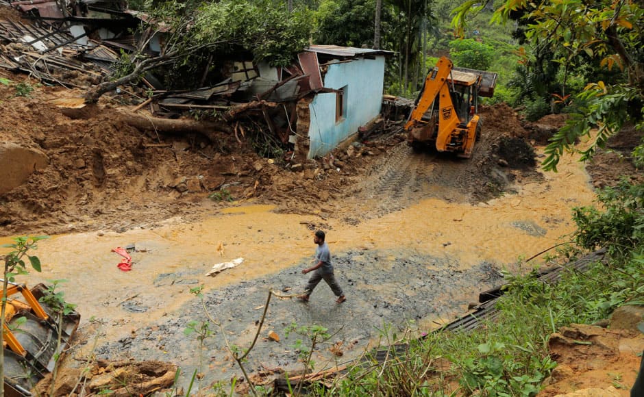 A Sri Lankan walks past a damaged house at the site of a mudslide at the Koslanda tea plantation in Badulla district, about 220 kilometers (140 miles) east of Colombo, Thursday, Oct. 30, 2014. Disaster Management Minister Mahinda Amaraweera estimated the number of dead in Wednesday's disaster would be fewer than 100, although villagers said the figure could easily exceed 200. (AP Photo/Eranga Jayawardena)