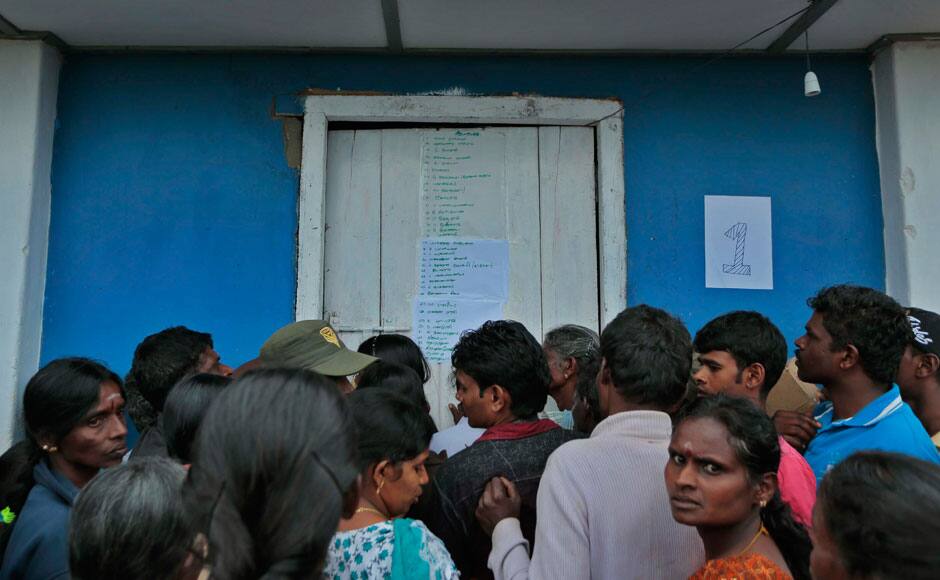 People gather to look at names of mudslide survivors displayed on a door at a relief center set up in a school in Punagala in Badulla district, about 140 miles (220 kilometers) east of Colombo, Sri Lanka, Thursday, Oct.30, 2014. Hundreds of desperate Sri Lankan villagers clawed through the wreckage of a deadly landslide Thursday, defying police orders after a top disaster official said there was no chance of finding more survivors in the broken red earth of the high-elevation tea plantation. There were conflicting reports of how many people were missing in the slide, which struck Wednesday morning in the island nation's central hills.(AP Photo/Eranga Jayawardena)