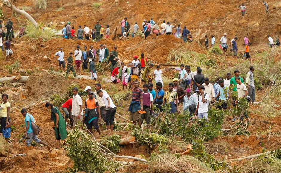 Sri Lankans stand on mud and sludge at the site of a mudslide at the Koslanda tea plantation in Badulla district, about 220 kilometers (140 miles) east of Colombo, Thursday, Oct. 30, 2014. Disaster Management Minister Mahinda Amaraweera estimated the number of dead in Wednesday's disaster would be fewer than 100, although villagers said the figure could easily exceed 200. (AP Photo/Eranga Jayawardena)