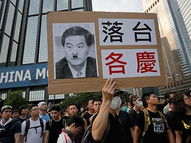 Protesters raises a placard with a defaced picture of Hong Kong's Chief Executive Leung Chun-ying outside a flag-raising ceremony he attended. AP