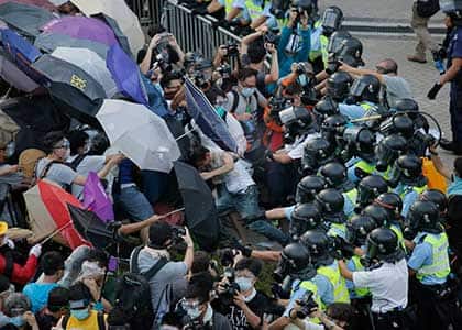 Riot police use pepper spray against protesters after thousands of people block the main road to the financial Central district outside the government headquarters in Hong Kong. Associated Press
