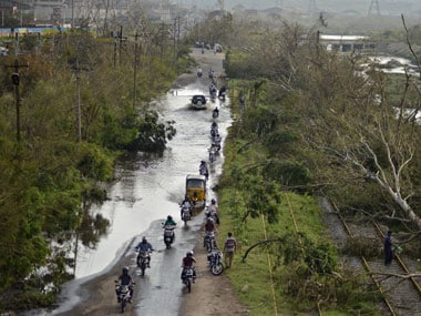 Vehicles move through a flooded road next to the trees fallen over railway tracks after being damaged by Cyclone Hudhud. Reuters