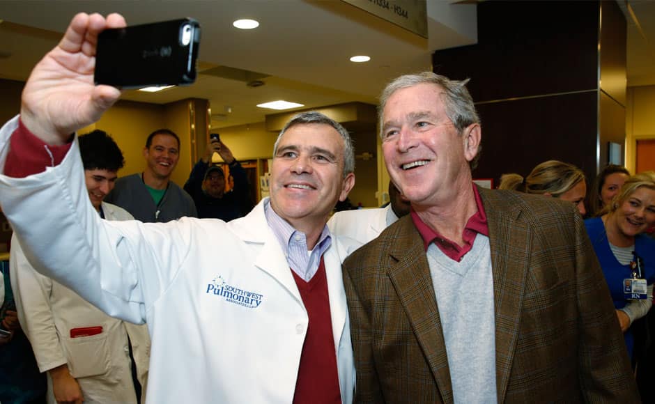Dr. Munir Hazbun takes a selfie with former President George W. Bush, Friday, Nov. 7, 2014, at Texas Health Presbyterian Hospital of Dallas. The city calmly marked the end of its Ebola crisis on Friday, when the last of the 177 people who were being monitored for symptoms of the deadly virus were to be cleared at midnight. (AP Photo/The Dallas Morning News, David Woo)