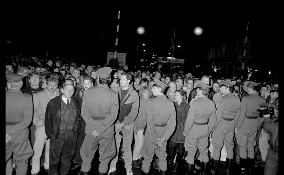 East German soldiers cordon off the border line in front of West Berliners waiting to welcome East Berlin citizen before crossing the border at the Allied checkpoint Charlie near the Berlin Wall after the opening of the East German border was announced in Berlin, November 9, 1989. REUTERS/Fabrizio Bensch (GERMANY ANNIVERSARY POLITICS SOCIETY) - RTR25N8A