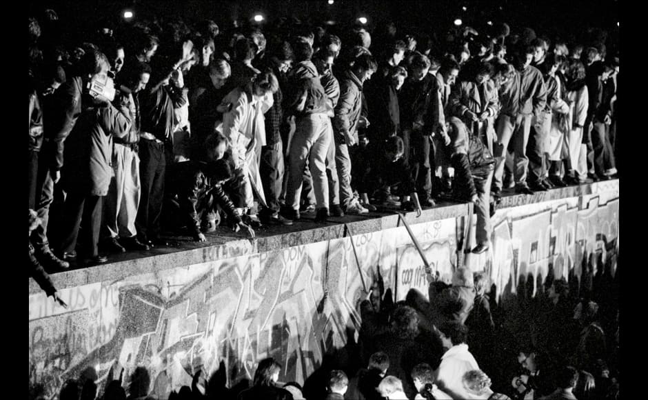 East and West German citizens celebrate as they climb the Berlin wall at the Brandenburg gate after the opening of the East German border was announced in Berlin, November 9, 1989. REUTERS/Fabrizio Bensch (GERMANY ANNIVERSARY POLITICS) - RTR25N8N