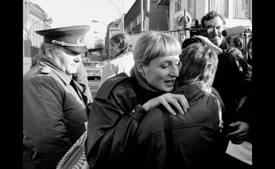 An East Berlin citizen (C) embraces a West Berlin woman while an East German border soldier watches on at the border checkpoint Invalidenstrasse after the opening of the East German border was announced in Berlin, November 9, 1989. REUTERS/Fabrizio Bensch (GERMANY ANNIVERSARY POLITICS) - RTR25OWE