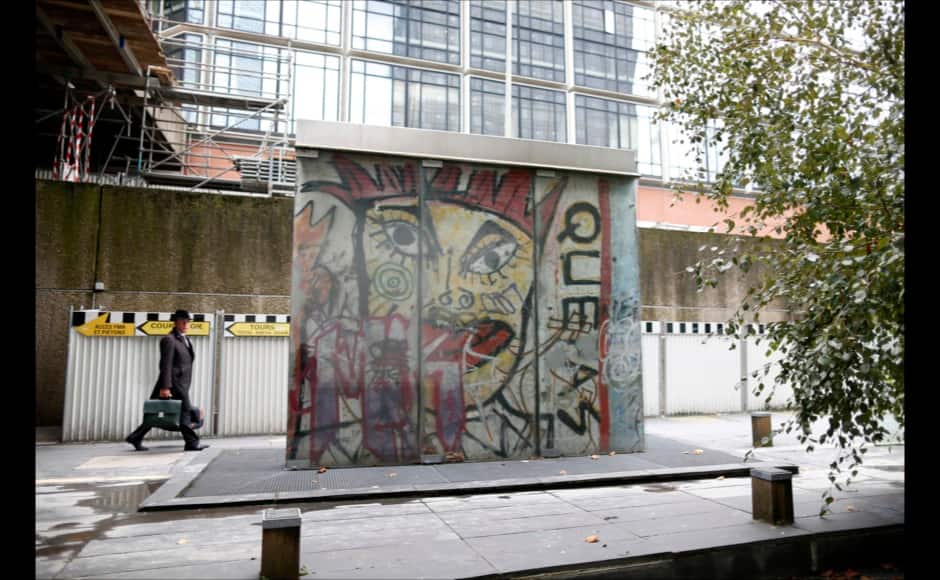 A man walks near a piece of the Berlin Wall in La Defense business district in Courbevoie October 16, 2014. The municipality of Courbevoie bought the piece of wall for 300.000 Deutsche Marks in 1990. The segment shows a painting of Kiddy Citny. On November 9, Germany will celebrate the 25th anniversary of the fall of the Berlin Wall. To mark the event Reuters Photographers around the world captured images of segments of the wall, which are kept as monuments in many countries from Taiwan to South Africa and Costa Rica. The Berlin Wall, which divided West Berlin from the communist East after it was built in 1961, was the most potent symbol of the Cold War. At least 136 people were killed or died at the Wall, most of them while trying to escape. On November 9, 1989, following huge protests in East Berlin, the wall was breached and thousands of people poured into West Berlin. Picture taken October 16, 2014. REUTERS/Charles Platiau (FRANCE - Tags: SOCIETY ANNIVERSARY CONFLICT) ATTENTION EDITORS - PICTURE 15 OF 32 FOR WIDER IMAGE STORY 'THE BERLIN WALL AROUND THE WORLD' SEARCH '25 BERLIN' FOR ALL IMAGES - RTR4CLP8