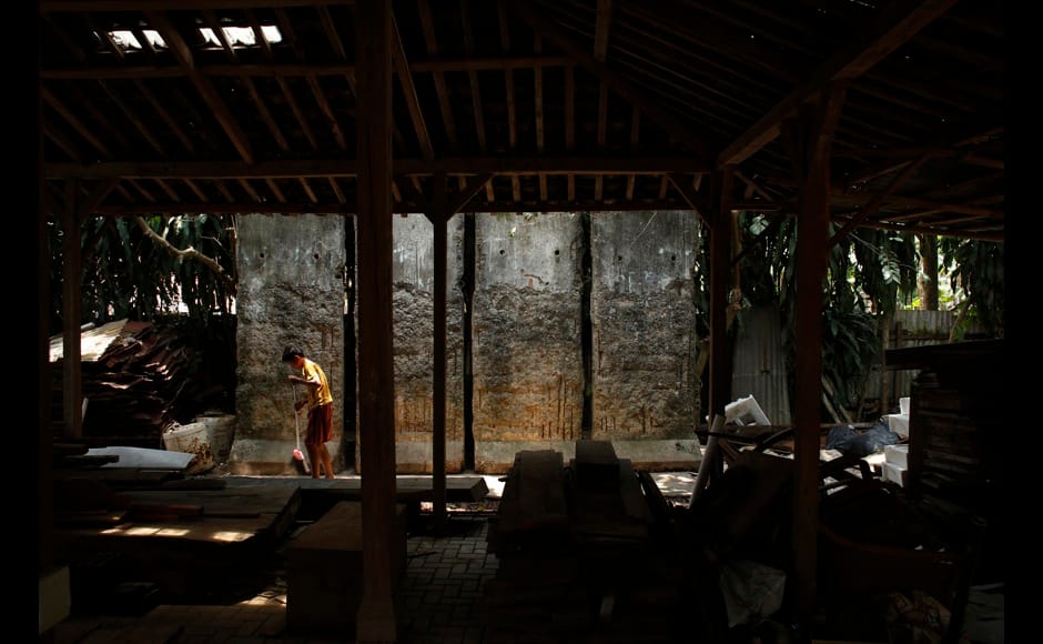 A child sweeps in front of four pieces of the Berlin Wall at Teguh Ostenrik's workshop in Pondok Petir village in Depok, Indonesia's West Java province October 22, 2014. Indonesia sculptor Teguh Ostenrik bought four original sections of the Berlin wall to Indonesia in 1990. On November 9, Germany will celebrate the 25th anniversary of the fall of the Berlin Wall. To mark the event Reuters Photographers around the world captured images of segments of the wall, which are kept as monuments in many countries from Taiwan to South Africa and Costa Rica. The Berlin Wall, which divided West Berlin from the communist East after it was built in 1961, was the most potent symbol of the Cold War. At least 136 people were killed or died at the Wall, most of them while trying to escape. On November 9, 1989, following huge protests in East Berlin the wall was breached and thousands of people poured into West Berlin. Picture taken October 22, 2014. REUTERS/Beawiharta (INDONESIA - Tags: SOCIETY ANNIVERSARY CONFLICT) ATTENTION EDITORS - PICTURE 29 OF 32 FOR WIDER IMAGE STORY 'THE BERLIN WALL AROUND THE WORLD' SEARCH '25 BERLIN' FOR ALL IMAGES - RTR4CLQ7