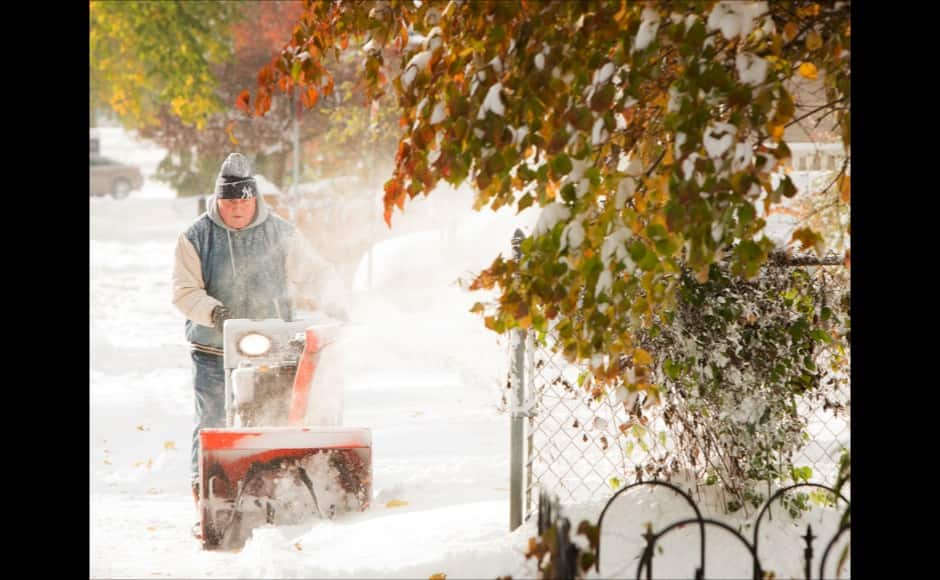A man blows snow from his sidewalk in Buffalo, New York, November 19, 2014. An autumn blizzard dumped a year's worth of snow in three days on Western New York state, where five people died and residents, some stranded overnight in cars, braced for another pummeling expected later on Wednesday. REUTERS