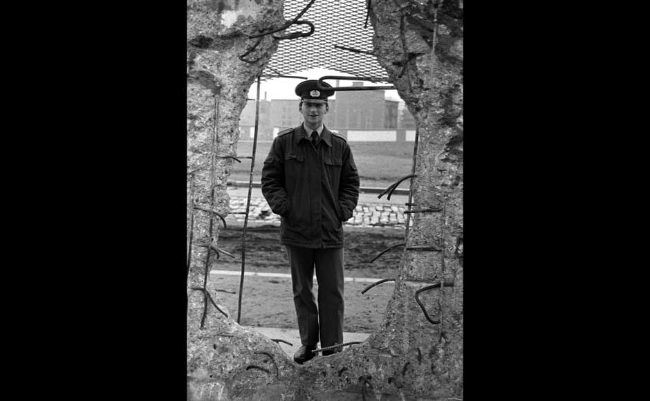 FILE PHOTO 8FEB1990 - An East German border soldier looks through a large hole into the Berlin Wall after the opening of the East German border was announced in this February 8, 1990 file photo. The 10th anniversary off the 