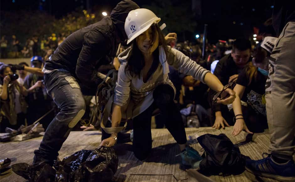 A pro-democracy protester climbs onto a divider to leave as riot police attempt to clear the demonstration site, close to the chief executive office in Hong Kong December 1, 2014. Hundreds of Hong Kong pro-democracy activists scuffled with police on Sunday as they tried to encircle government headquarters, defying orders for protesters to retreat after more than two months of demonstrations. REUTERS
