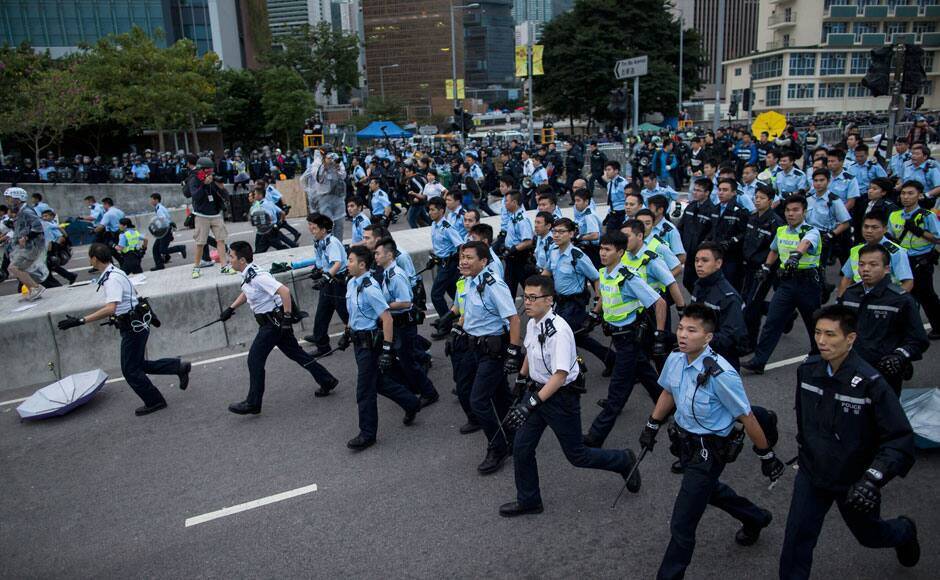 Police officers hold batons as they clear a demonstration site near the office of the Chief Executive in Hong Kong December 1, 2014. Hong Kong police baton-charged and pepper-sprayed thousands of pro-democracy demonstrators in the early hours of Monday who were trying to encircle government headquarters, defying orders to retreat after more than two months of protests. REUTERS