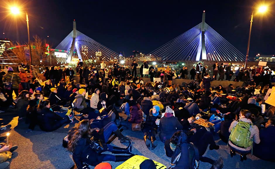 Thousands of protestors sit down on the Charlestown Bridge, blocking traffic into Downtown Boston, during a demonstration against the deaths of two unarmed black men at the hands of white police officers in New York City and Ferguson, Mo., in Boston, Thursday, Dec. 4, 2014. At rear is the Zakim Bunker Hill Bridge. AP