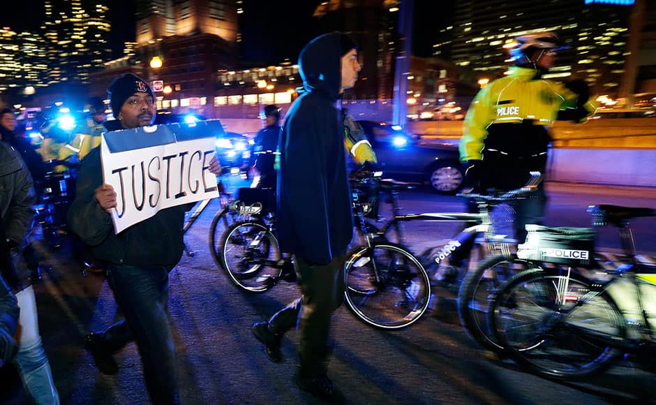 Protestors pass as police block an entrance to a tunnel to Logan Airport during a demonstration against the deaths of two unarmed black men at the hands of white police officers in New York City and Ferguson, Mo., in Boston, Thursday, Dec. 4, 2014. AP 