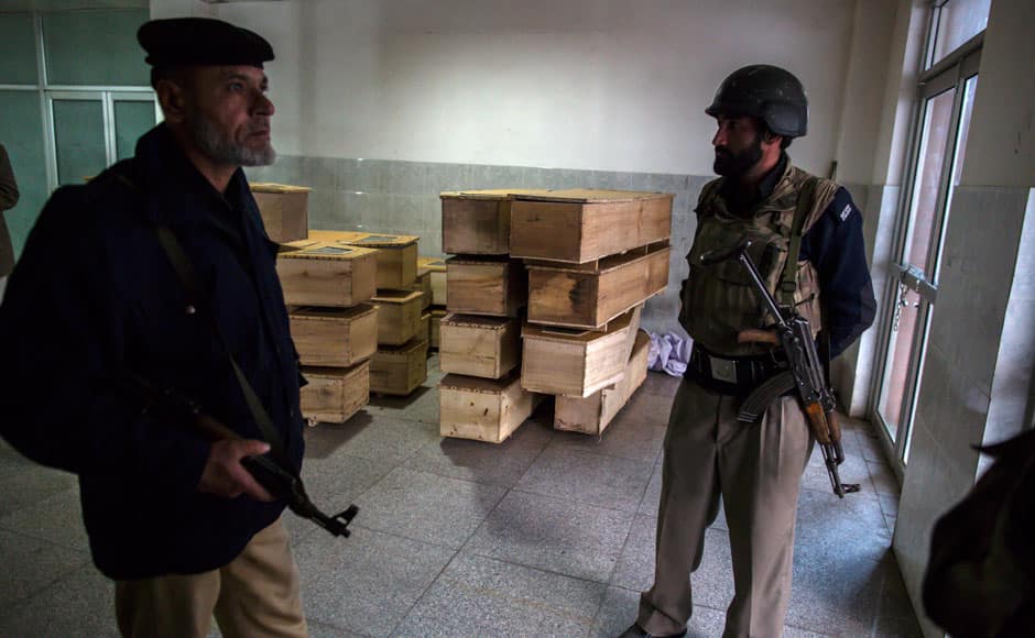 Policemen stand beside empty coffins at the hospital after an attack by Taliban gunmen on the Army Public School in Peshawar December 16, 2014. At least 132 students and nine staff members were killed on Tuesday after Taliban gunmen broke into a school in the Pakistani city of Peshawar and opened fire, witnesses said, in the bloodiest massacre the country has seen for years. REUTERS