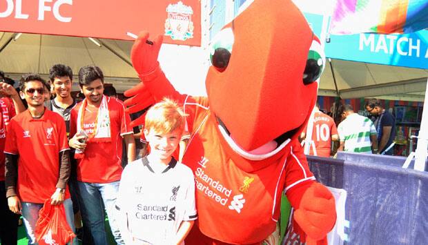 A young fan poses with Liverpool's mascot.