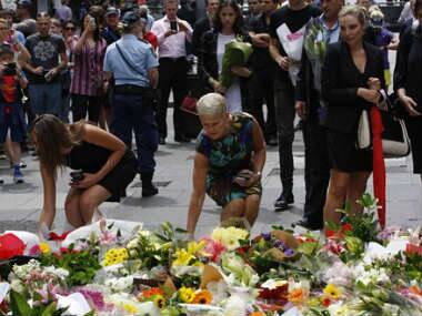 Women offer flowers at a makeshift memorial in Sydney, Australia. AP 