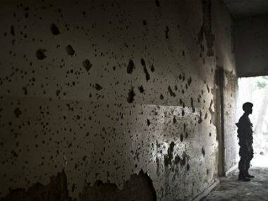 A Pakistani army officer, stands by a wall riddled with bullet marks, inside the Army Public School attacked last Tuesday by Taliban gunmen, in Peshawar, Pakistan. AP 