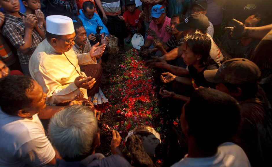 Relatives pray during the burial of Hayati Lutfiah, a passenger of AirAsia QZ8501, at a cemetery in Surabaya January 1, 2015. Heavy seas held back divers waiting to inspect the possible wreck of an AirAsia Indonesia jet off Borneo on Thursday and an aviation official said it could be a week before the black box flight recorders are found. REUTERS