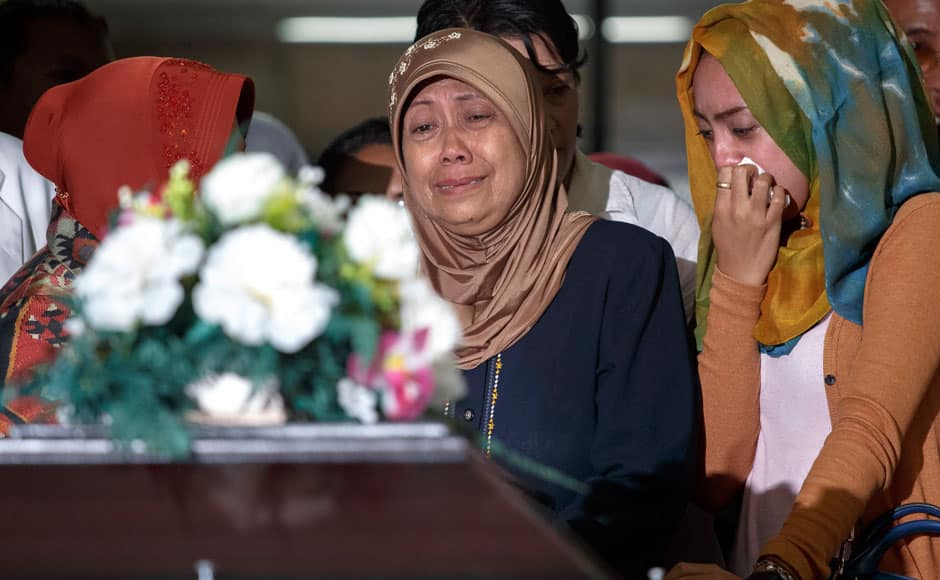 The mother (C) and other family members of Hayati Lutfiah, a passenger of Airasia QZ8501, cry upon receiving her remains at Bhayankara Hospital in Surabaya January 1, 2015. Divers waiting to inspect the possible wreck of the AirAsia Indonesia jet off Borneo were unable to resume operations because of heavy seas on Thursday and an aviation official said it could take a week to find the black box flight recorders. REUTERS
