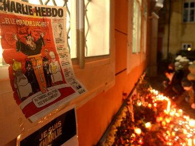 A Charlie Hebdo cover is seen next to a makeshift memorial site. AFP 