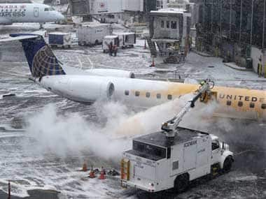 A man de-ices a plane during a light snow at a gate at LaGuardia Airport in New York: AP
