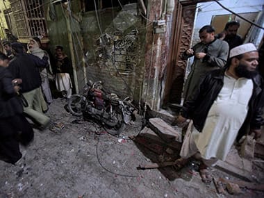 A Pakistani police officer and local residents gather next to a damage motorcycle at the site of a suicide bombing in Rawalpindi, Pakistan. PTI