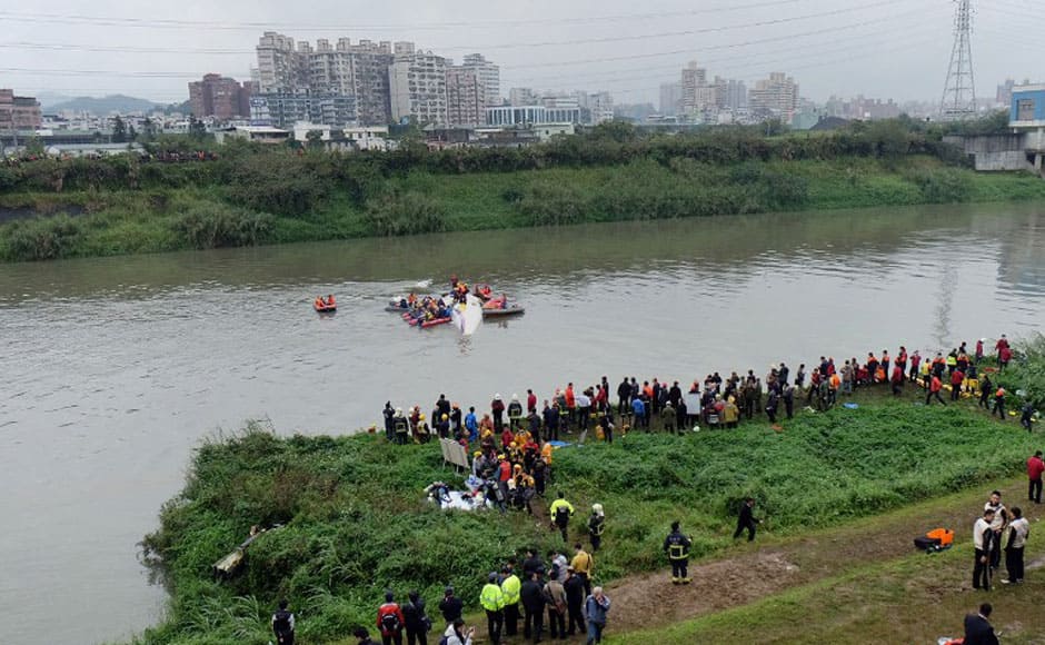 Rescue personnel work to free passengers from a TransAsia ATR 72-600 turboprop plane (C-in water) that crash-landed into a river outside Taiwan's capital Taipei in New Taipei City on February 4, 2015. The passenger plane with 58 people on board was on a domestic flight when it plunged into the river, with at least 10 people rescued and dozens trapped inside, according to television reports. AFP