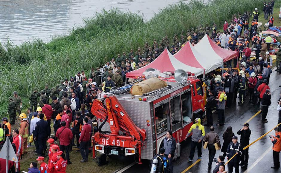 Rescue personnel, military and members of the media line up along the shore as rescue operations continue to free passengers from a TransAsia ATR 72-600 turboprop plane (not pictured) that crash-landed into a river (at L) outside Taiwan's capital Taipei in New Taipei City on February 4, 2015. The low-flying passenger plane, TransAsia Flight GE235 with 58 people on board, clipped a road bridge and plunged into the river outside Taiwan's capital with at least three feared dead and dozens trapped inside. AFP
