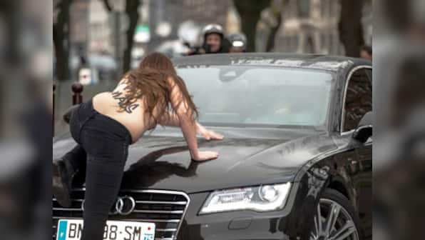 Topless Femen activists jump on Dominique Strauss-Kahn's car as he arrives for trial