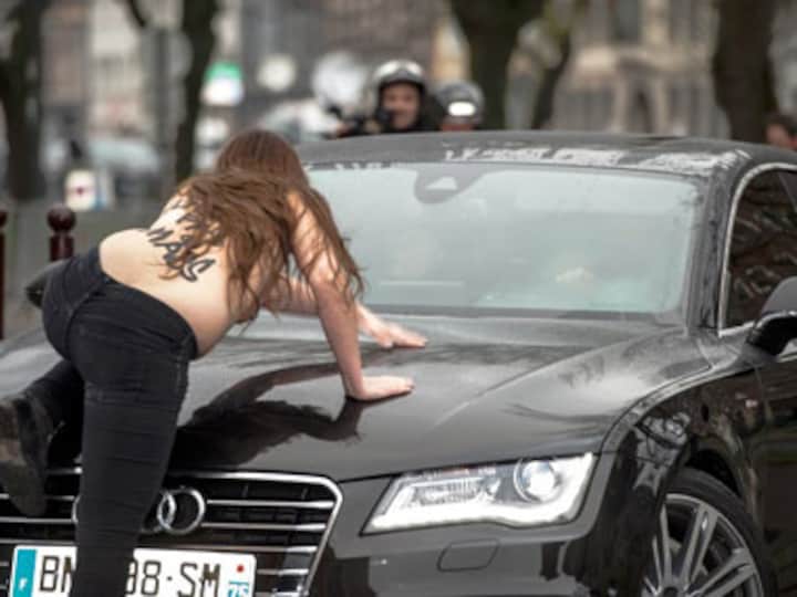 Topless Femen activists jump on Dominique Strauss-Kahn's car as he arrives for trial