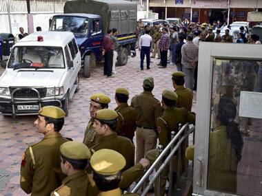 Cops stand guard as Petroleum document leak accused are bought to Patiala House court in New Delhi on Saturday. PTI