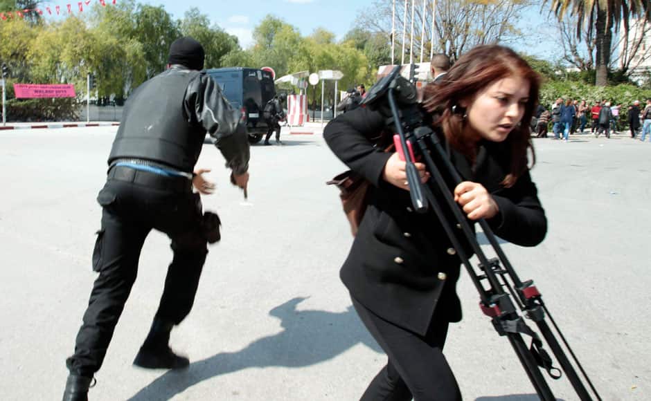 Police officers and a journalist run outside the parliament in Tunis March 18, 2015. Gunmen in military uniforms stormed Tunisia's national museum, killing 17 foreign tourists and two Tunisians on Wednesday in one of the worst militant attacks in a country that has largely escaped the region's 