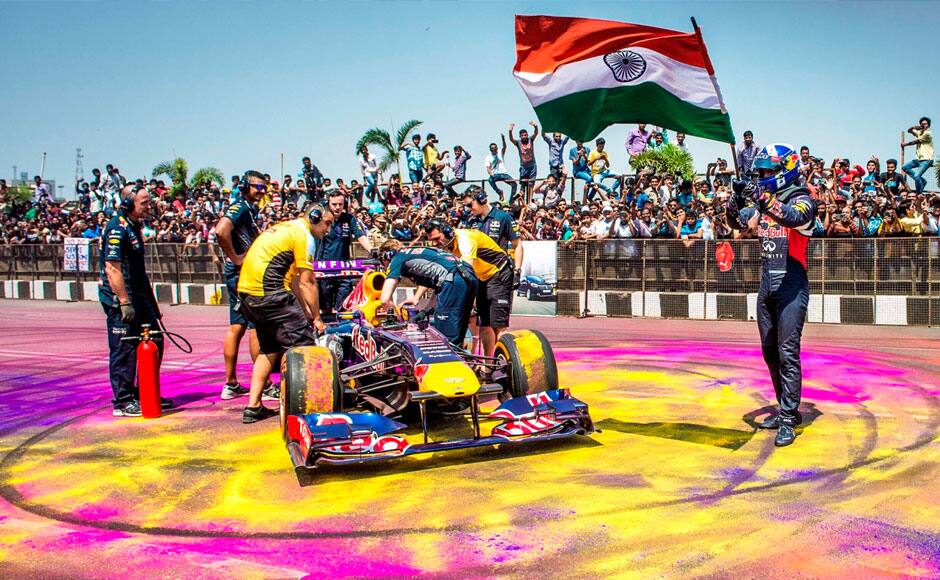 Pit crew attend to the F1 car of former Formula One racing driver David Coulthard of the Infiniti Red Bull Racing team, as he waves the Indian flag after driving twice around the Hussain Sagar lake in Hyderabad, India on April 5, 2015. Solaris Images