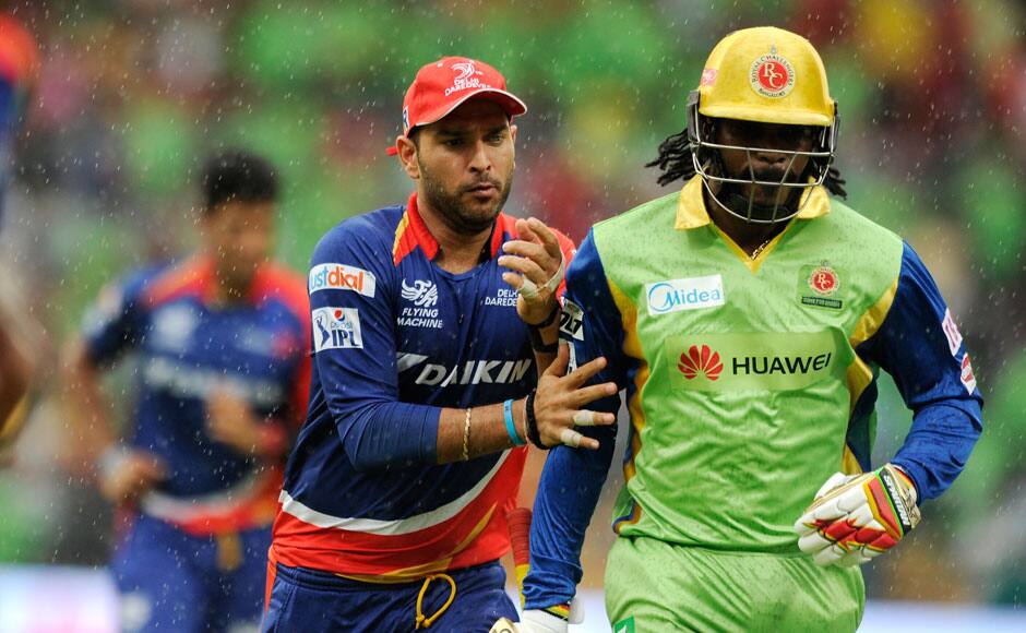 Yuvraj Singh of Delhi Daredevils tries to push Chris Gayle of Royal Challengers Bangalore jokingly while they run back to the pavilion as it starts to rain during match 55 of the Pepsi IPL 2015 (Indian Premier League) between The Royal Challengers Bangalore and The Delhi Daredevils held at the M. Chinnaswamy Stadium in Bengaluru, India on the 17th May 2015. sportzpics
