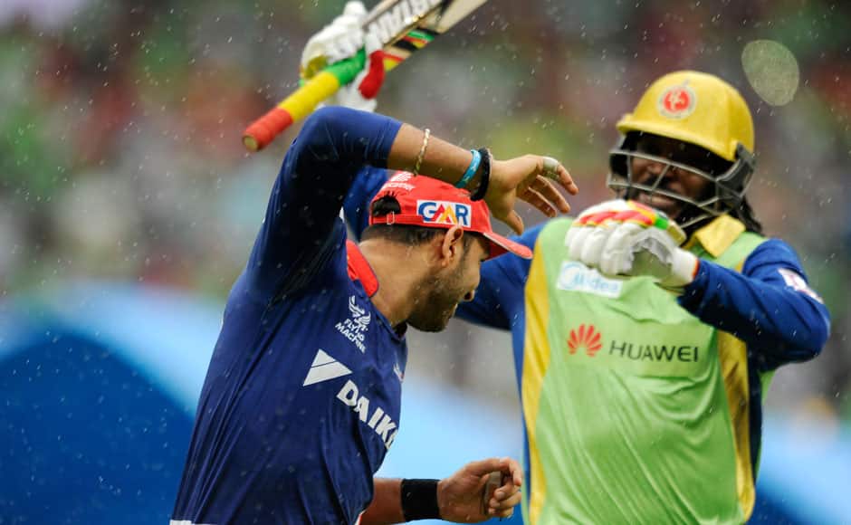 Chris Gayle of Royal Challengers Bangalore fakes to hit Yuvraj Singh of Delhi Daredevils with his bat while they run back to the pavilion as it starts to rain during match 55 of the Pepsi IPL 2015 (Indian Premier League) between The Royal Challengers Bangalore and The Delhi Daredevils held at the M. Chinnaswamy Stadium in Bengaluru, India on the 17th May 2015. sportzpics