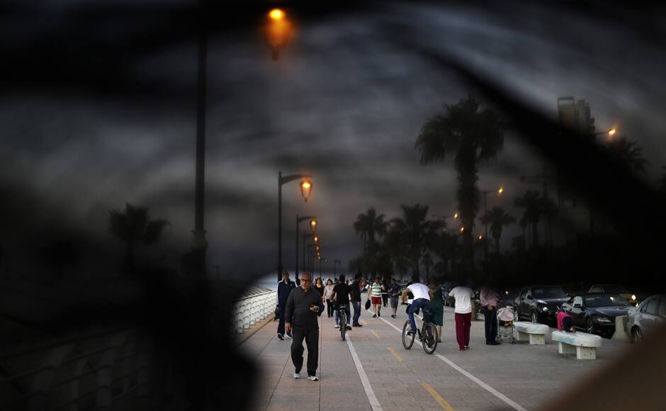 This Thursday, April 30, 2015 photo shows Lebanese citizens walking on the Corniche, or waterfront promenade in Beirut, Lebanon. This photo was shot through the lowered veil of a niqab, which is worn by some conservative Muslim women. The cloth allows women to follow a strict interpretation of their religious beliefs by preventing others from seeing their faces. (AP Photo/Hassan Ammar)