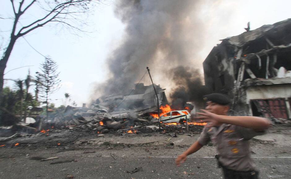 A police officer gestures at the crowd near the site where an Air Force cargo plane crashed in Medan, North Sumatra, Indonesia, Tuesday, June 30, 2015. An Indonesian Air Force Hercules C-130 plane with 12 crew aboard has crashed into a residential neighborhood in the country's third-largest city Medan. (AP Photo/Gilbert Manullang)