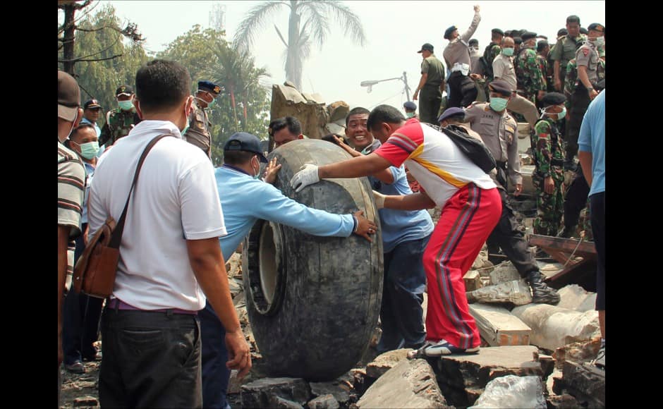 Military personnel remove an aircraft wheel at the site where an air force cargo plane crashed in Medan, North Sumatra, Indonesia, Tuesday, June 30, 2015. An Indonesian air force Hercules C-130 plane with 12 crew aboard has crashed into a residential neighborhood in the country's third-largest city Medan. (AP Photo/Dedy Zulkifli)